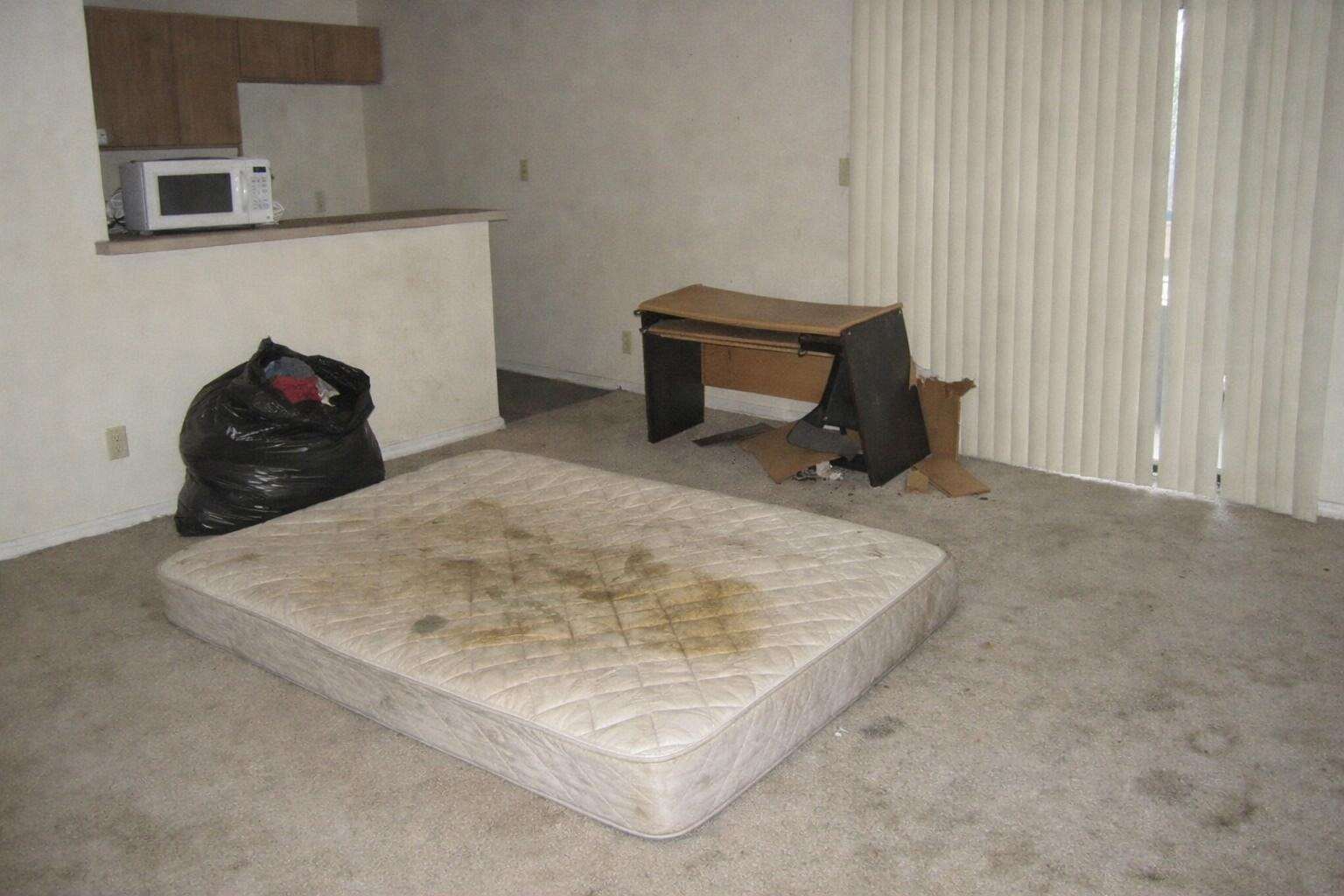A stained mattress left on the floor of a vacant apartment